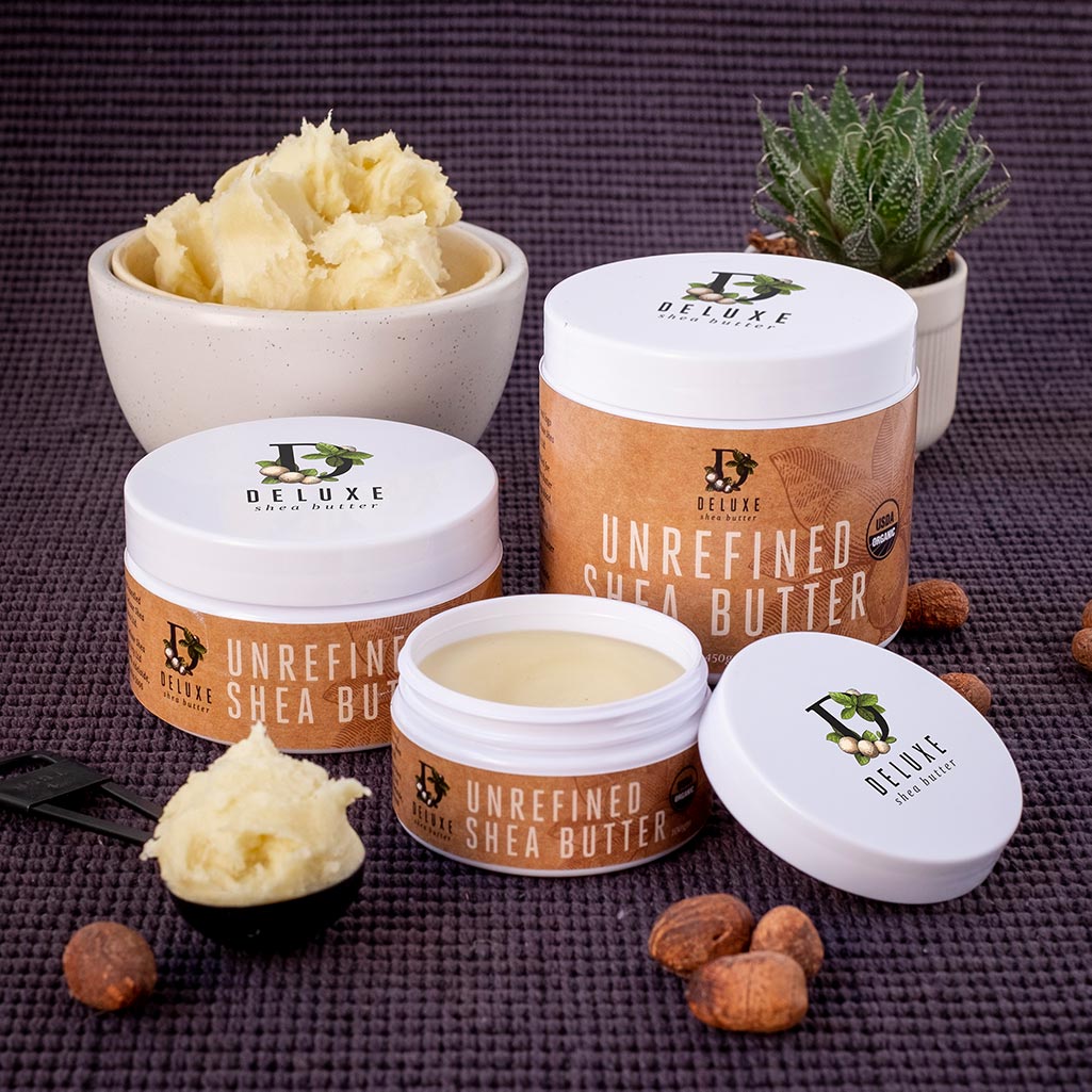 Raw Shea butter in a bowl, and a 100 gram, 250 gram, and 450 gram tub, with Shea nuts scattered around.